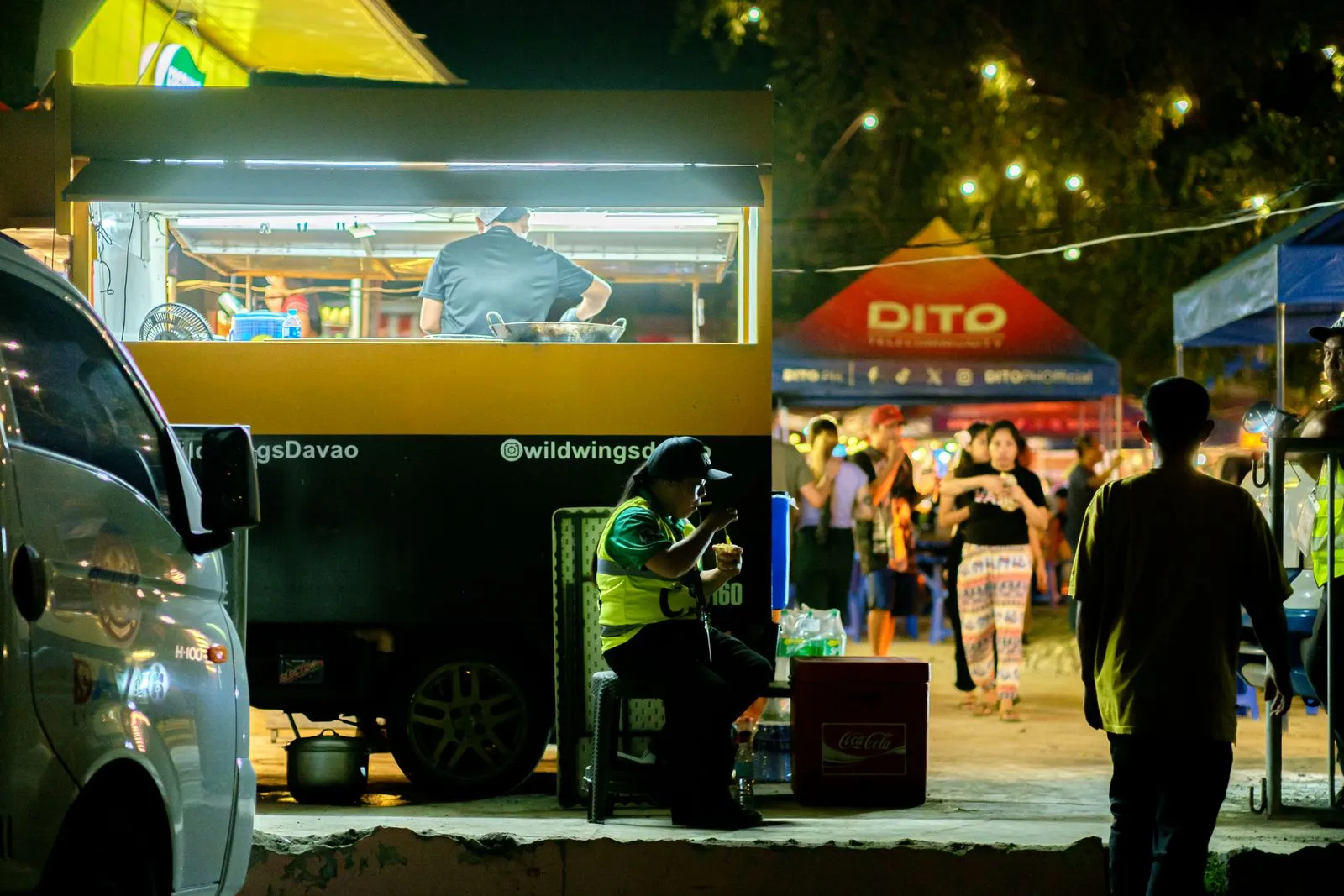 Lively outdoor night market with food stalls and people enjoying the atmosphere.